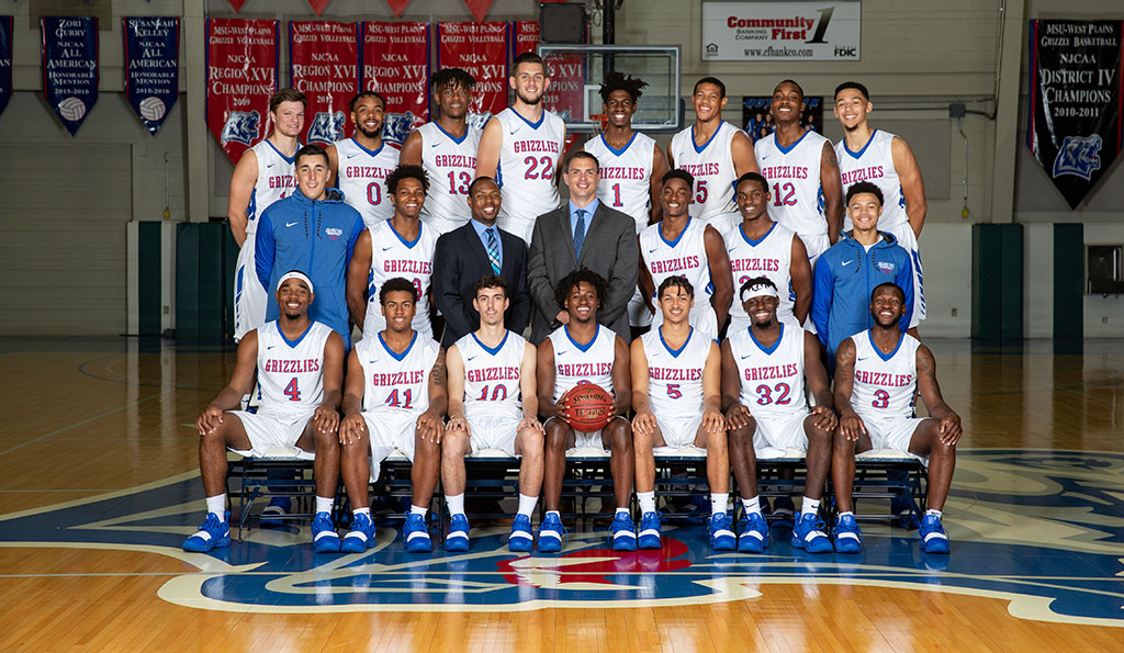 The 2018-19 Grizzly Basketball team is standing by row in the West Plains Civic Center arena.